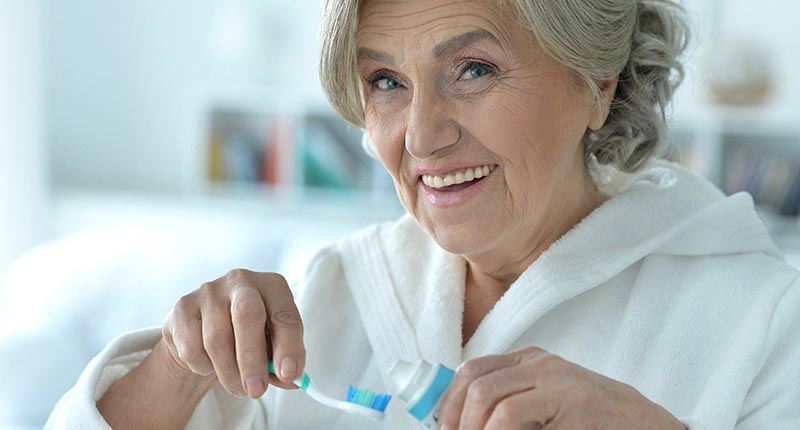 Woman with toothbrush ready to clean dentures